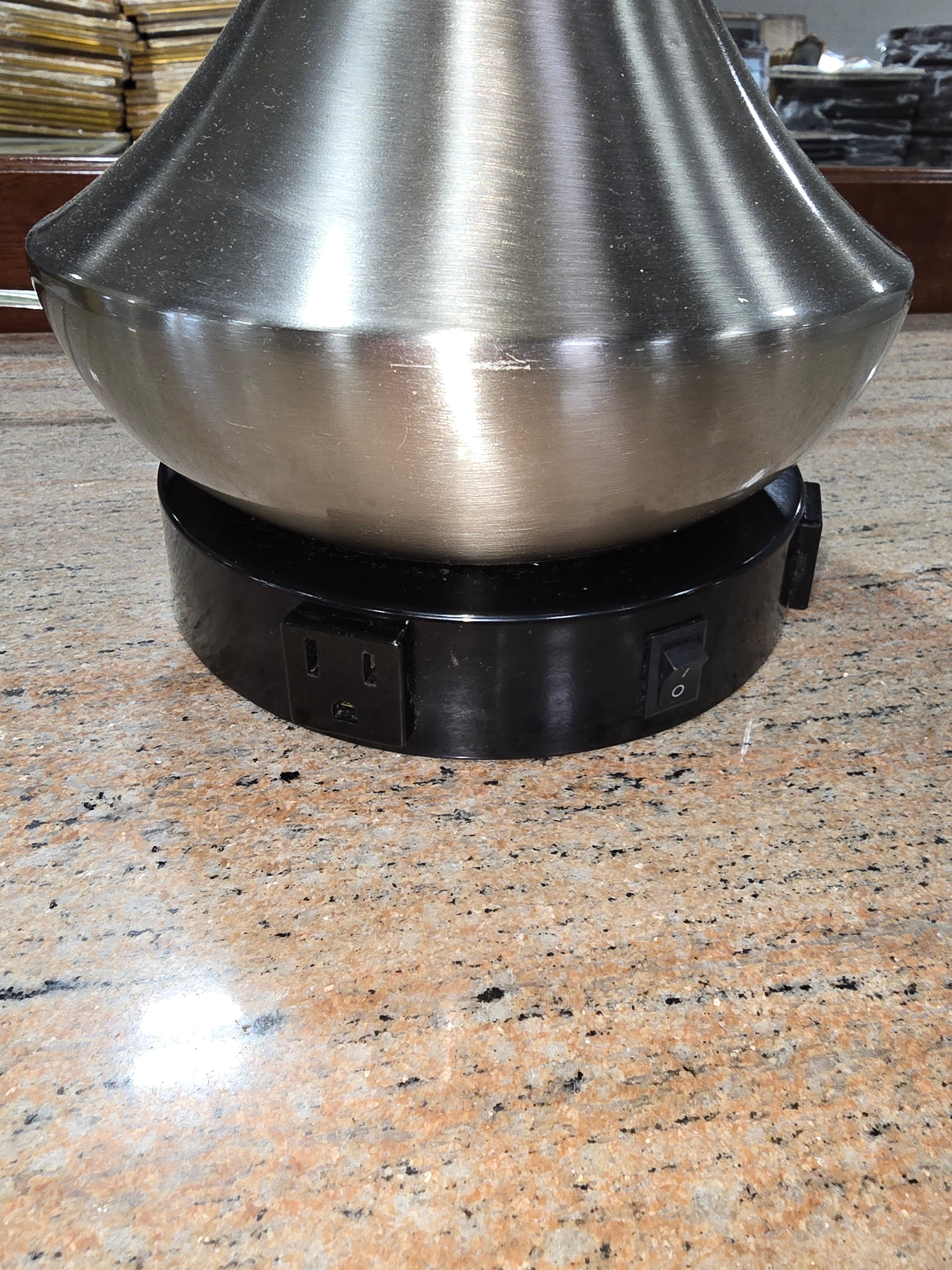 SHL close-up of brushed nickel table lamp base featuring dual built-in 120V power outlets sourced from an upscale resort