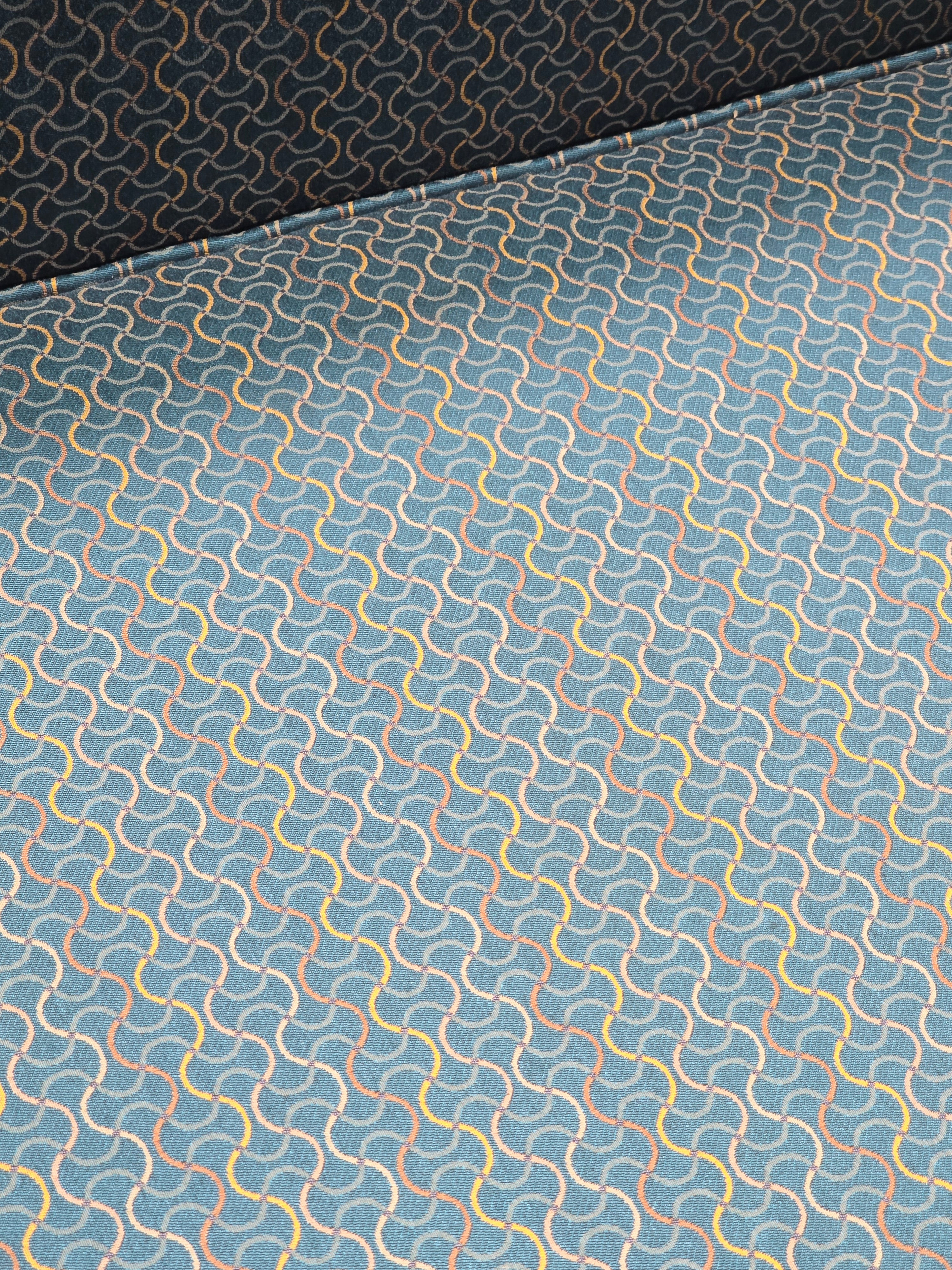 Close-up of the teal green geometric patterned upholstery on a used queen sleeper sofa from Southern Hospitality Liquidation.