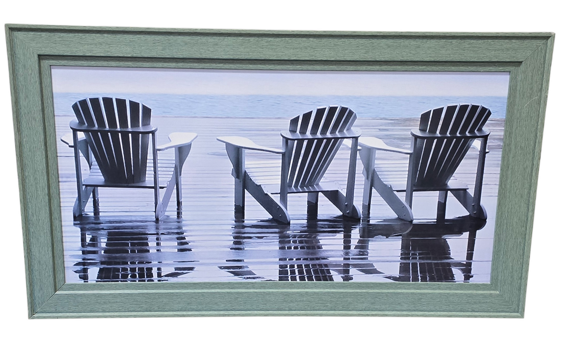 Framed wall art of Adirondack chairs on the beach by the ocean, used and in good condition