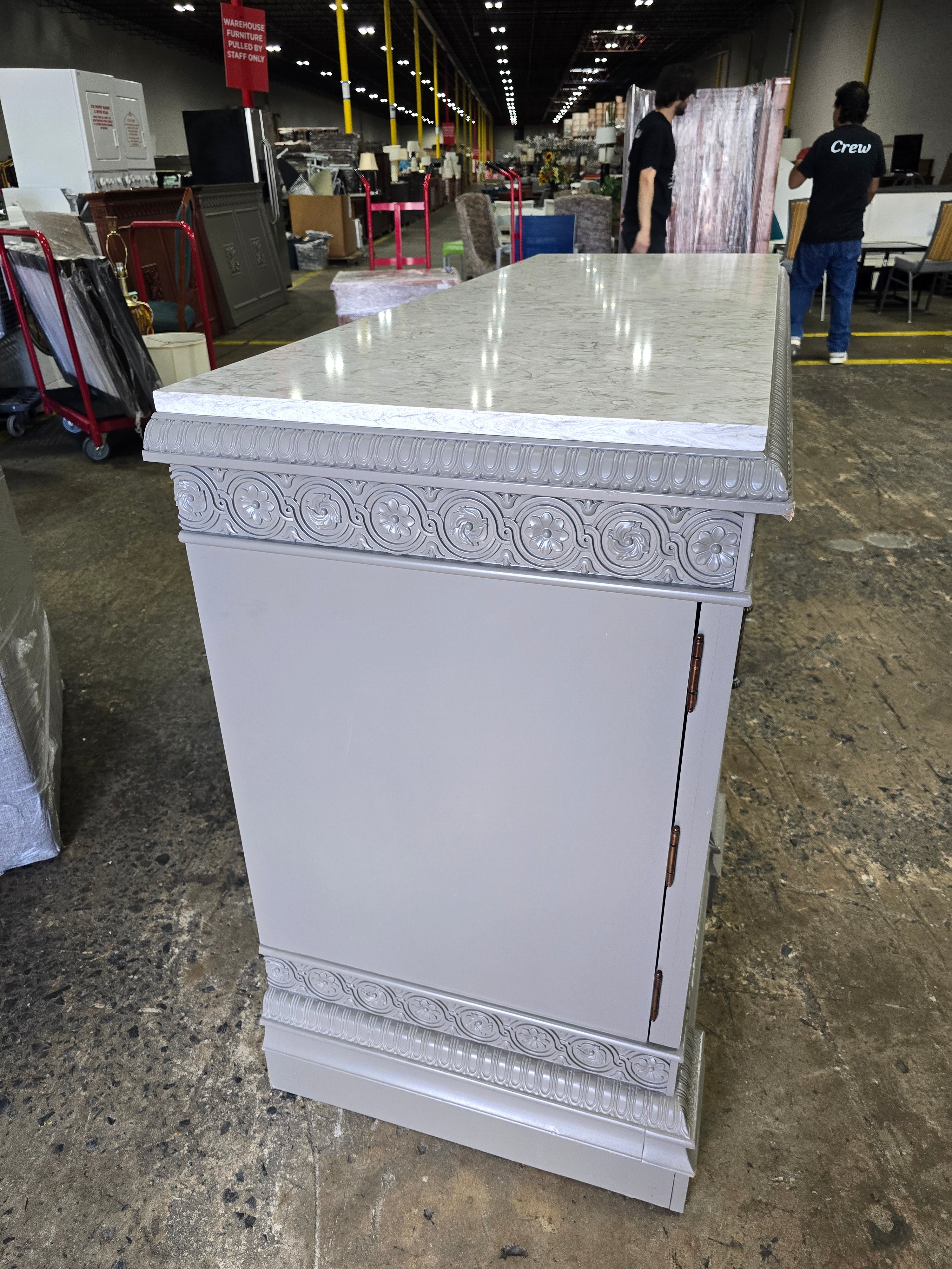 Side angle view of carved wood dresser with granite top