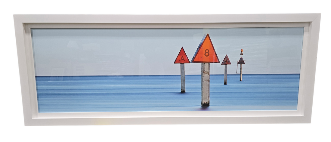 Framed coastal wall art of navigational boat markers in the ocean, used and in good condition