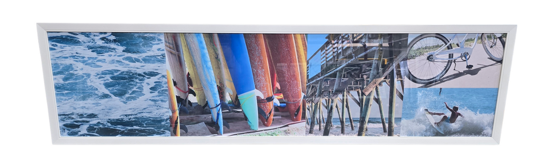 White framed panoramic coastal collage wall art featuring surfboards bicycle on sand and pier measuring 65 1/4 x 17.5, used and in good condition