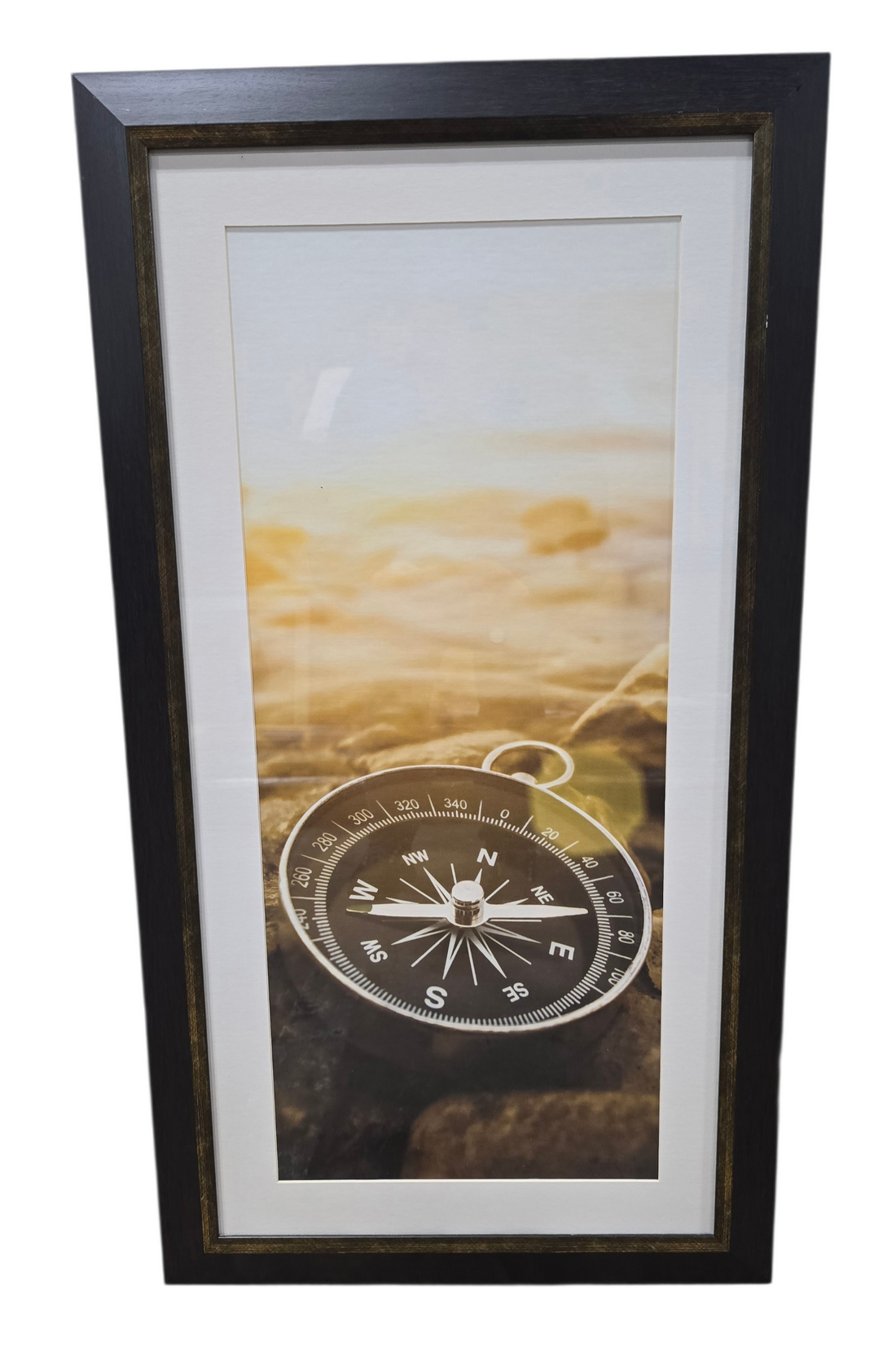Framed wall art of compass resting on shoreline stones, used and in good condition