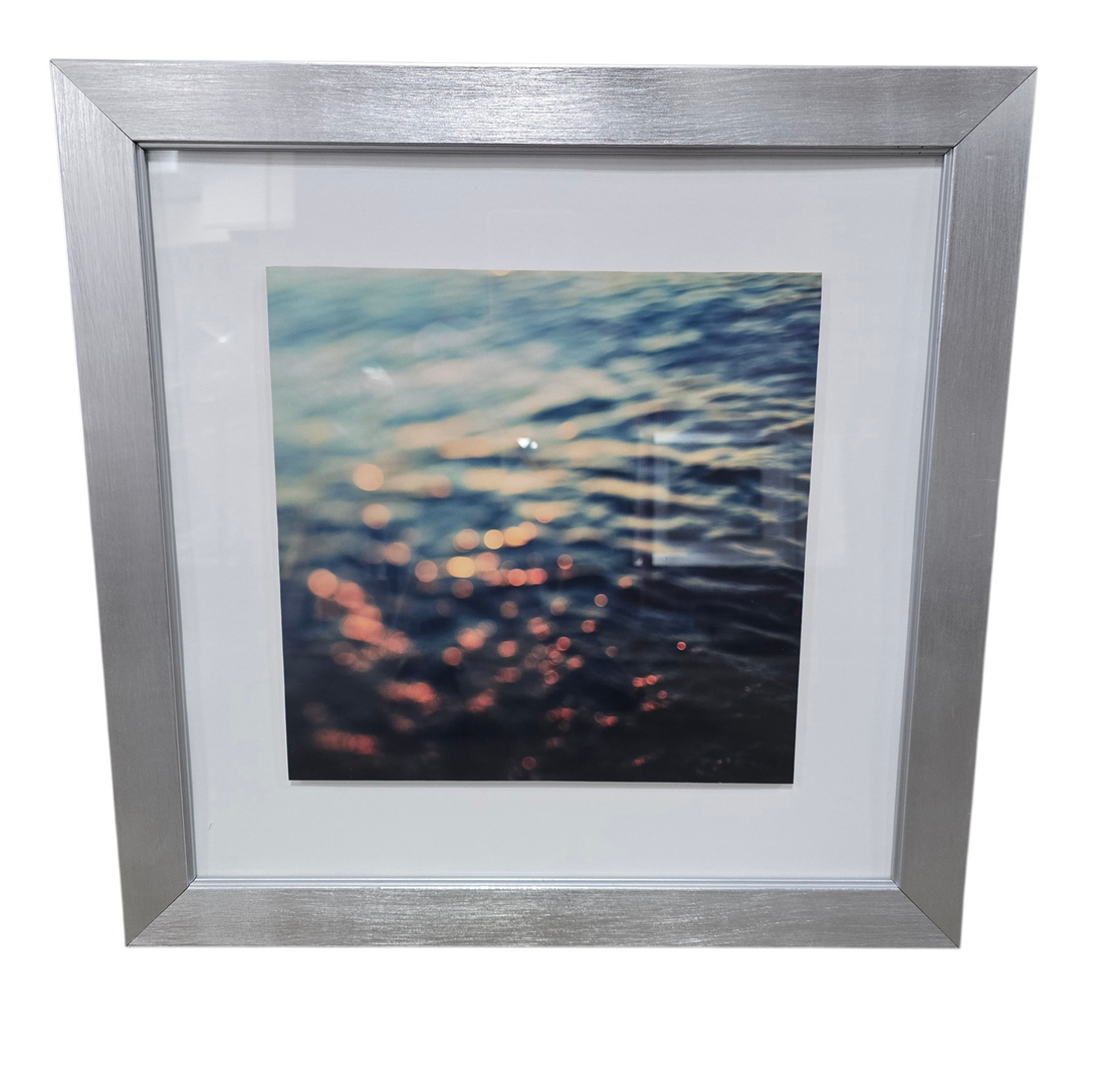 Silver framed abstract wall art showing blurred light reflecting on water surface measuring 18 1/4 x 18 1/4, used and in good condition