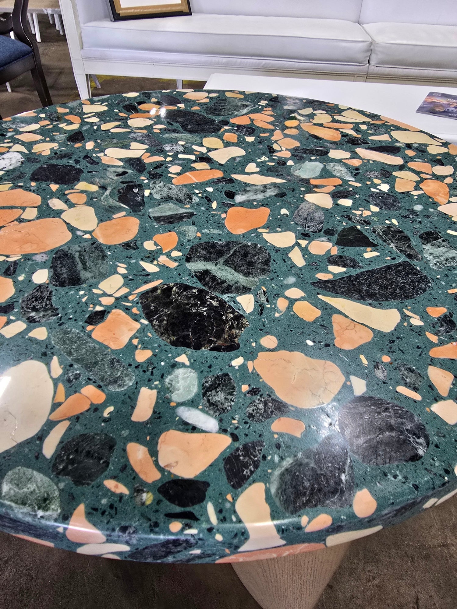 Close-up view of colorful terrazzo tabletop and natural wood pedestal base on modern accent table