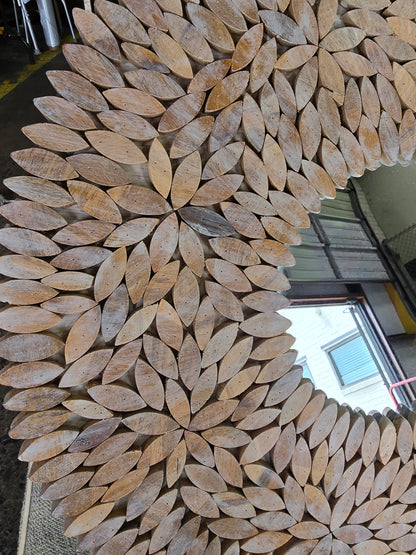 Close-up of the handcrafted wooden floral petal frame on a quality used 24-inch round wall mirror sourced from an upscale resort. Available in Cartersville, GA.