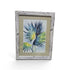 Framed blue and green tropical palm leaf artwork with distressed whitewashed frame
