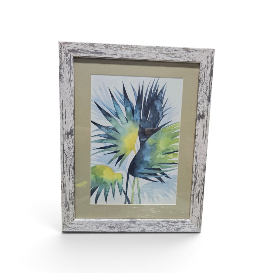 Framed blue and green tropical palm leaf artwork with distressed whitewashed frame