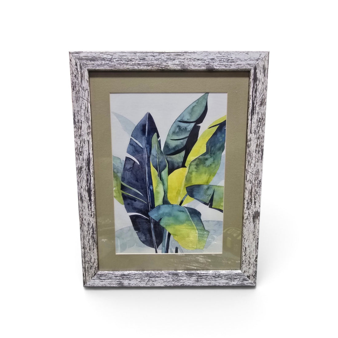 Framed tropical botanical artwork with blue green and yellow leaves and distressed whitewashed frame