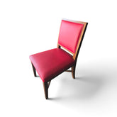 Used red upholstered dining chair shown at an angle with warm brown wood frame and tapered legs, SHL