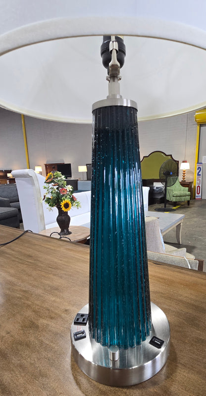 Close-up of used blue ribbed glass table lamp featuring built-in USB ports and dual power outlets, sourced from an upscale resort and available at SHL.