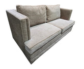 Angled view of used gray upholstered sleeper sofa with nailhead trim.