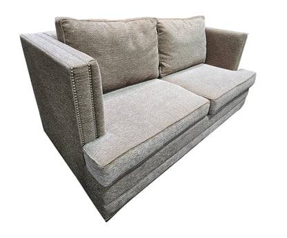 Angled view of used gray upholstered sleeper sofa with nailhead trim.