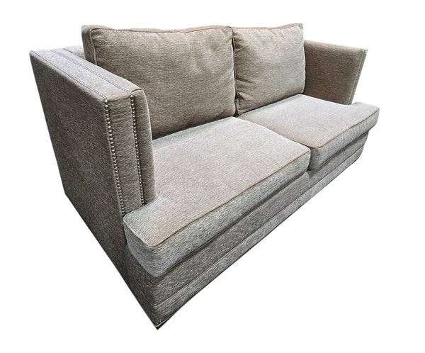 Angled view of used gray upholstered sleeper sofa with nailhead trim.