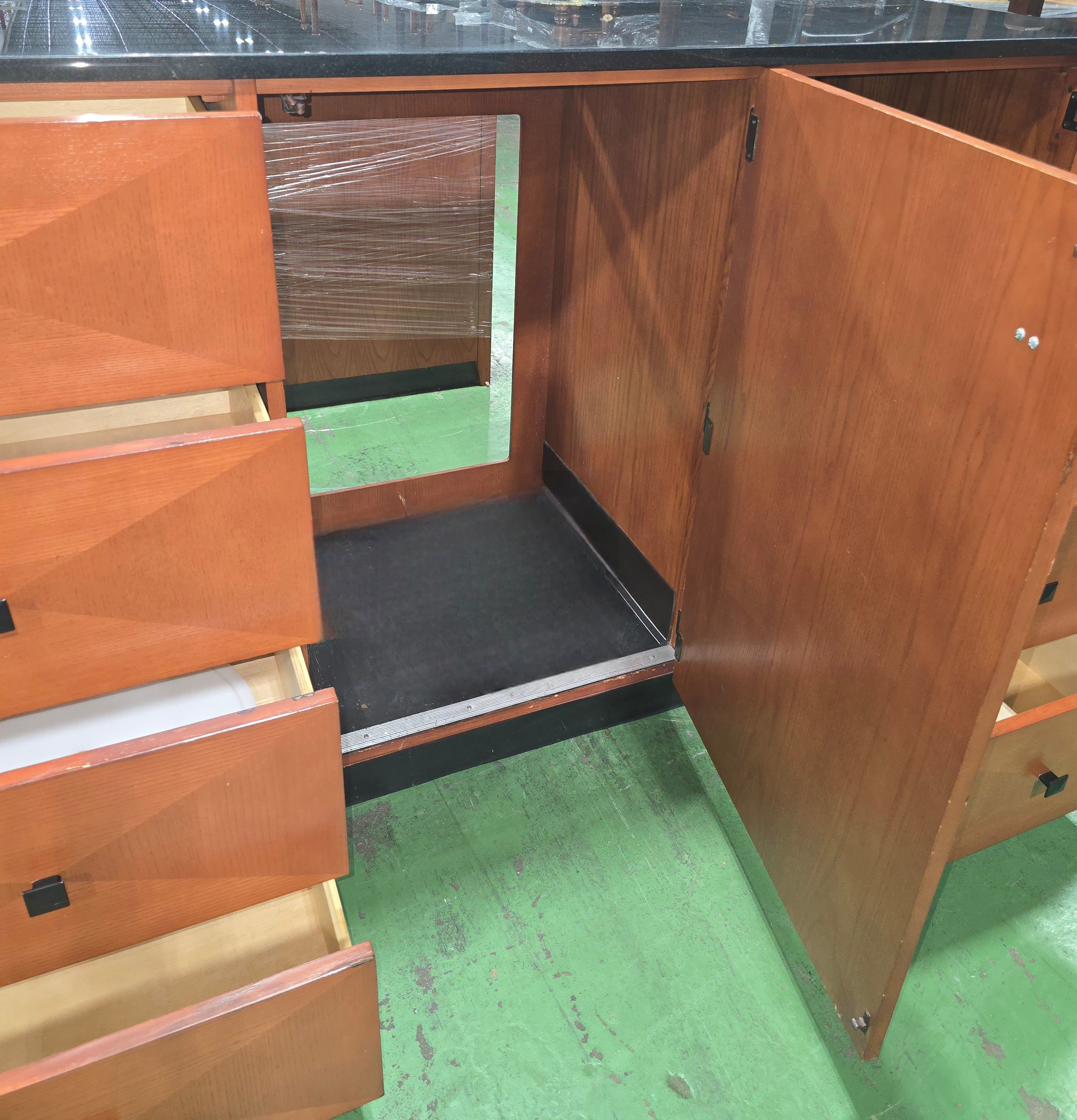 Open mini fridge cabinet inside a used Kimball Hospitality dresser with black granite top from Southern Hospitality Liquidation