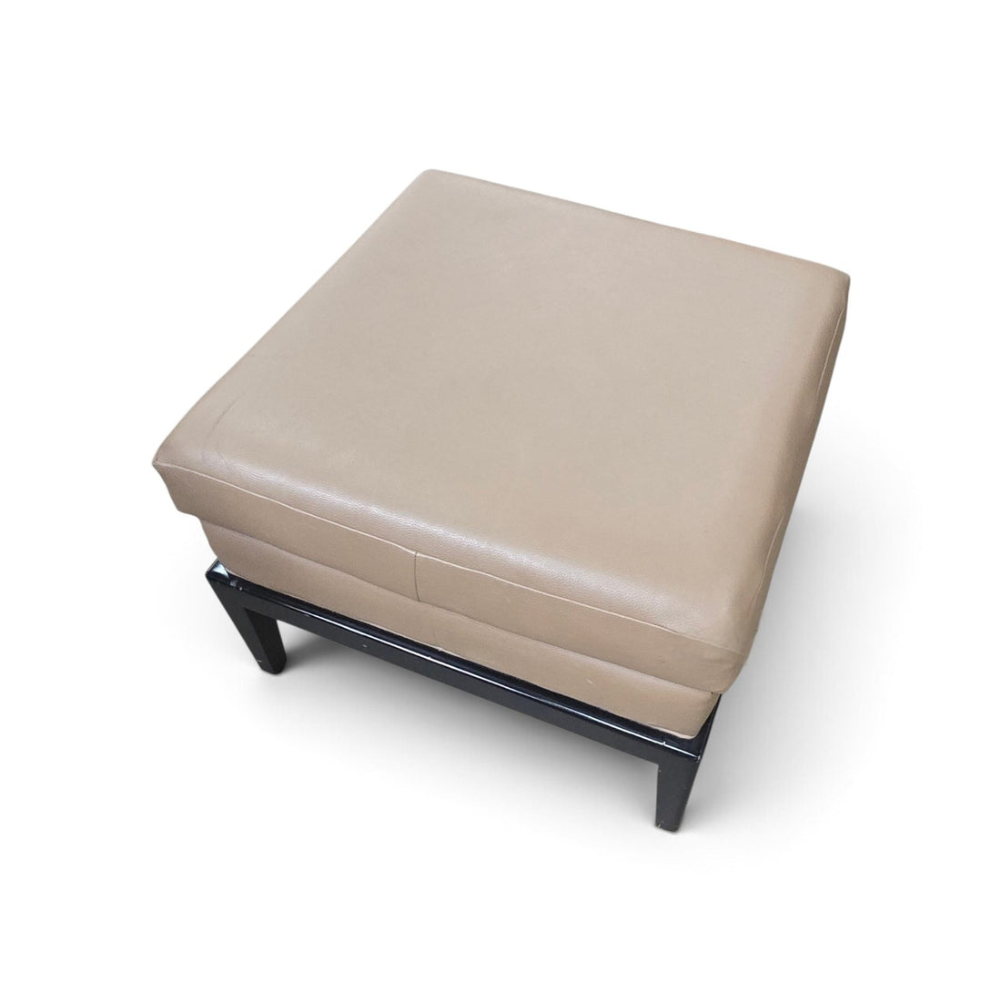 Top view of a used tan vinyl ottoman with padded cushion and black wood base from Southern Hospitality Liquidation.