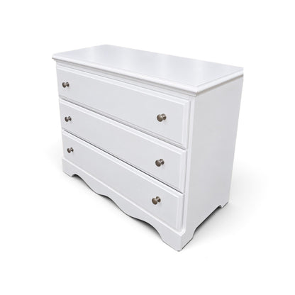Angled view of used white slim chest with three drawers and silver knobs, SHL